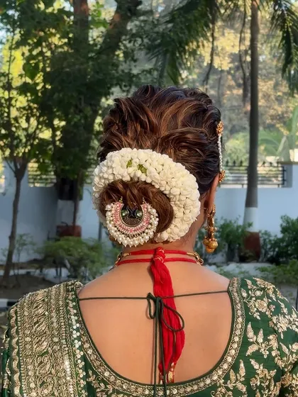 A close-up of the bridal bun, showing the intricate detail of the fresh flower gajra and hair accessory.
