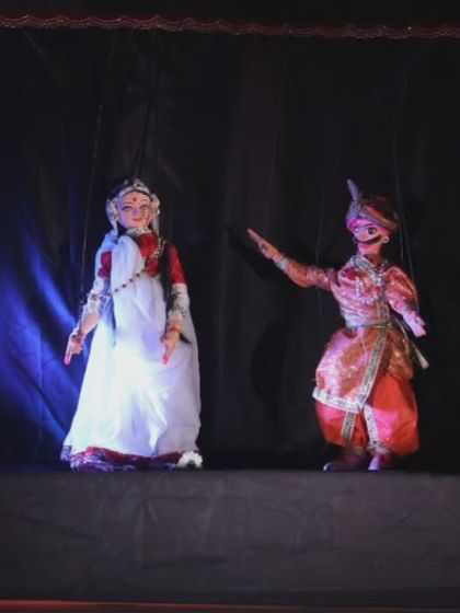 A scene from 'Giridhar Naagar Ki Meera' featuring the puppets of Meera Bai and a companion. The performance traces Meera's journey of unshakeable faith and devotion.