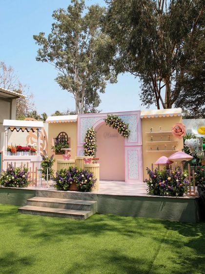 A whimsical, market-themed birthday party setup on the stage at Backyard. The pastel colors and floral arrangements create a charming and unique party atmosphere.