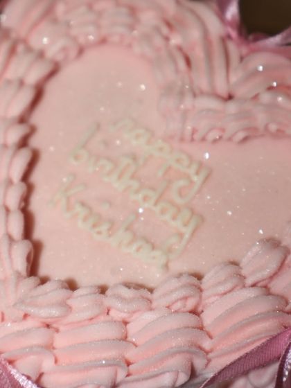 A close-up on the sparkly "Happy Birthday" message on our pastel pink heart cake, showing the glittery finish that makes it extra special.