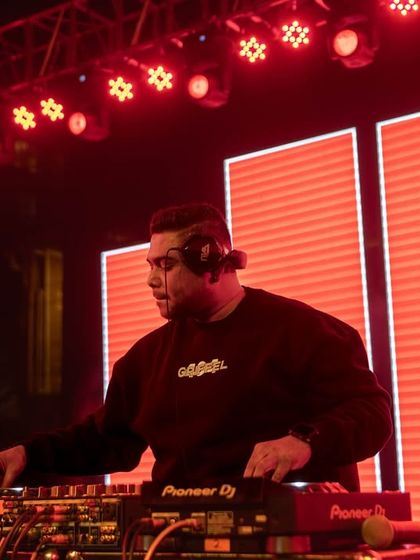 Bathed in red light, I'm locked into the music, mixing tracks on my Pioneer decks. The visuals are a huge part of the experience I create.