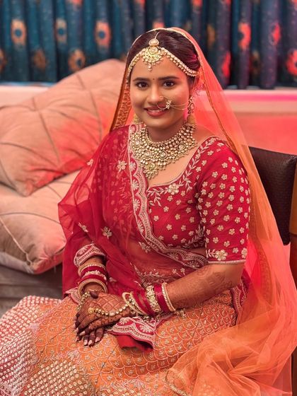 A beautiful portrait of the bride in her red and orange lehenga. The makeup is minimal yet effective, enhancing her features and matching her skin tone perfectly.