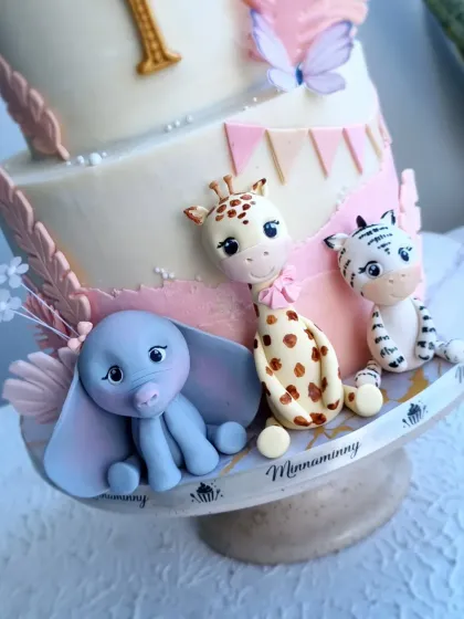 A close-up of the adorable fondant elephant, giraffe, and tiger on the pink safari cake.