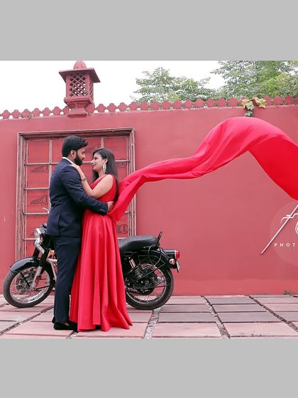 A dynamic pre-wedding shot featuring our motorcycle prop against a bold red wall. The flowing fabric adds a sense of motion and drama, perfect for couples looking for a cinematic feel in their photos.