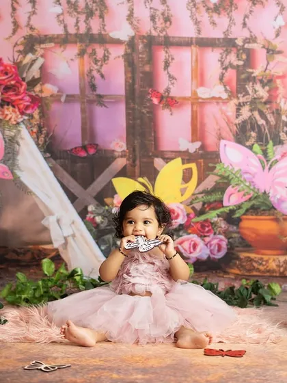 The birthday girl in her enchanted forest, surrounded by flowers and butterflies. This setup creates a beautiful backdrop for a first birthday.