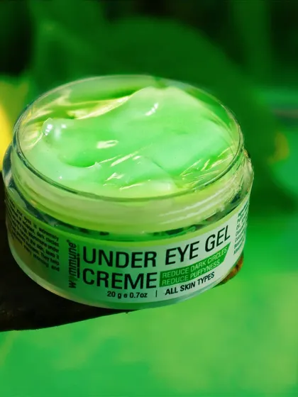 A close-up of the Wommune under-eye gel, focusing on its smooth, cooling texture against a vibrant green backdrop.