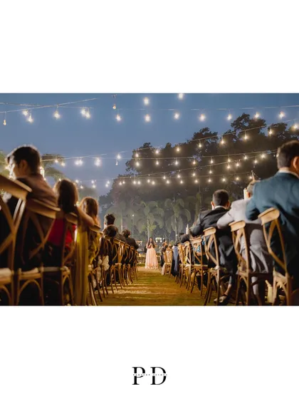 The bride's entrance at the sit-down dinner. The aisle between the long tables, under a sky of fairy lights, creates a beautiful and dramatic path.