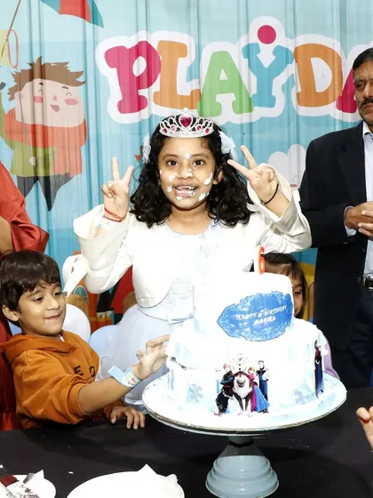 The birthday girl, complete with a tiara and a smile, poses with her Frozen-themed cake. The joy on her face is why I love my job.