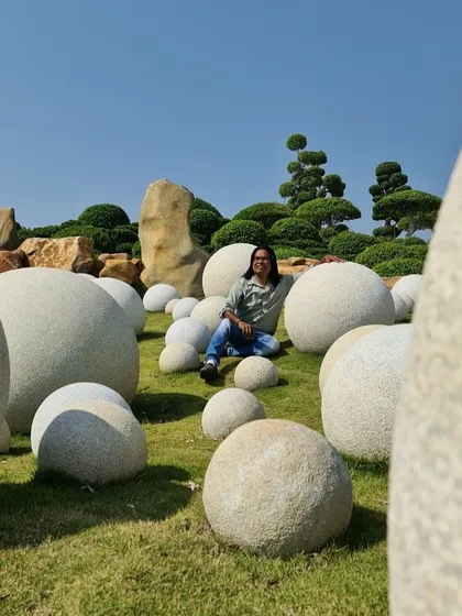 A moment of peace in our large-scale botanical garden project in Hyderabad. This design features whimsical stone spheres scattered across a manicured lawn, contrasted with sculpted topiary trees, creating a surreal and artistic landscape.
