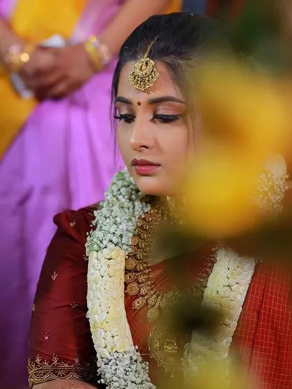 A candid shot of a bride during her wedding rituals. Her makeup looks flawless and radiant throughout the long ceremony.