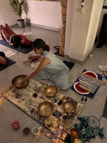 A close-up of the beautiful setup for a sound bath, featuring Tibetan bowls, candles, and other healing instruments.