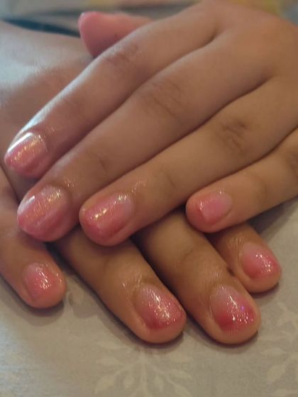 A soft pink glitter ombre on short, natural nails. The glitter is focused on the tips, providing a subtle sparkle that's perfect for everyday wear.