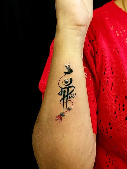 This custom calligraphy piece combines 'Maa' and 'Paa' (Mother and Father) into a single, flowing design. It’s a tribute to the foundation of family, adorned with a feather and beads.