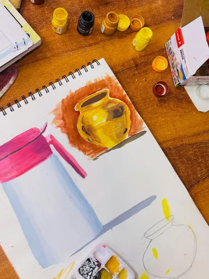 A work in progress shot showing the initial layers of color on a metal pot painting and a sketch of another object. This demonstrates the process of building up a composition.