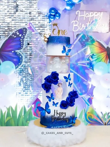 A full view of the blue butterfly cake, featuring multiple tiers, kinetic wings, and beautiful blue rose details.