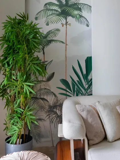 A detail shot of a sofa in 'House in the Hills', with a beautiful tropical wallpaper in the background, bringing a touch of nature indoors.