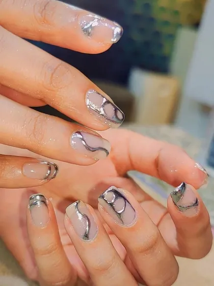 A sleek and futuristic design. These short, natural-shaped nails are adorned with 3D silver chrome swirls and shapes, creating a modern and edgy look.