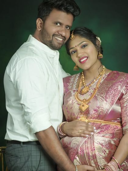 A beautiful studio portrait of a couple in traditional attire. Their smiles and close embrace radiate happiness and celebrate their journey to parenthood.