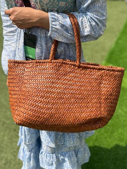 A close-up of our handwoven Juno tote in a classic timber brown. The intricate weaving pattern is a testament to the skill of our artisans.