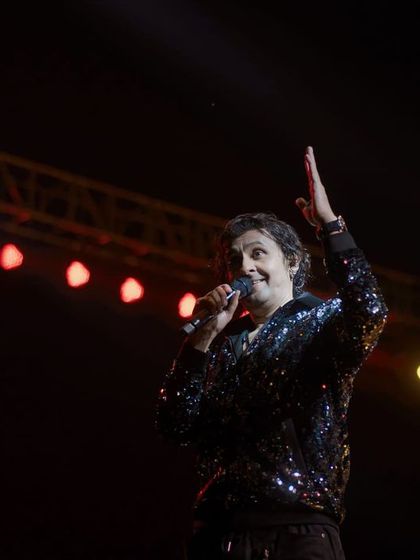 A side profile of Sonu Nigam interacting with the crowd. This angle provides a different perspective on the performance, showing the connection between the artist and his fans.