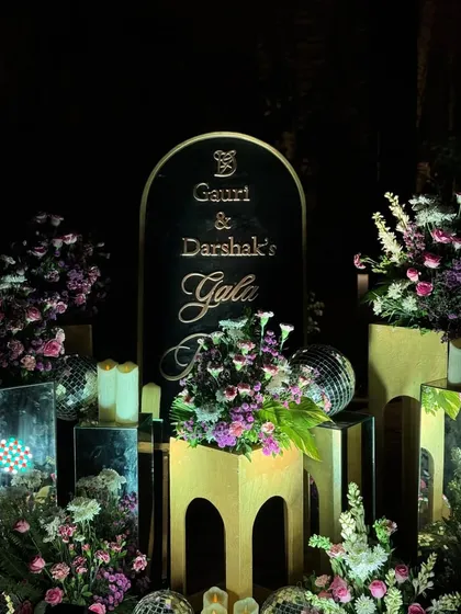 An elegant welcome sign for a gala dinner. The black and gold design, surrounded by floral arrangements, disco balls, and candles, set a sophisticated and celebratory tone for the evening.