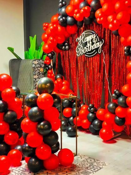 A bold red and black balloon arch with a fringe curtain backdrop. This setup is perfect for creating a dramatic and high-energy photo corner for a birthday party.