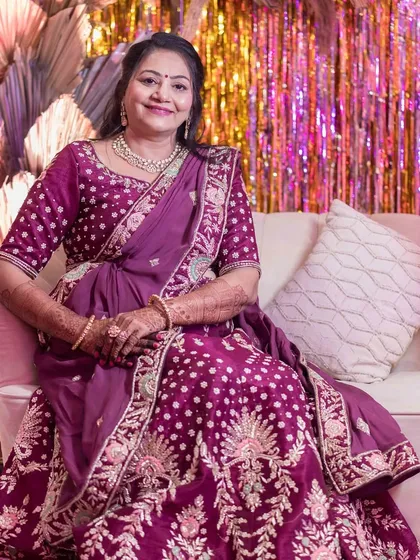 A seated portrait of the groom's mom. Her makeup looks flawless and comfortable, ensuring she can enjoy the festivities without any worries.