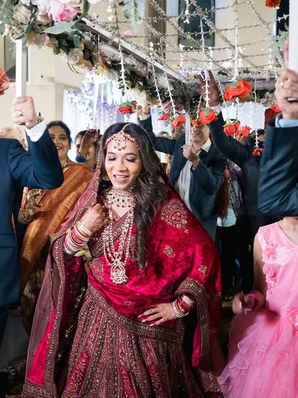 The bride makes her grand entrance under a phoolon ki chadar, surrounded by her happy family.