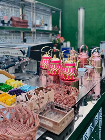 A close-up of the tea station, with a variety of tea bags and beautifully designed pink and copper teapots.