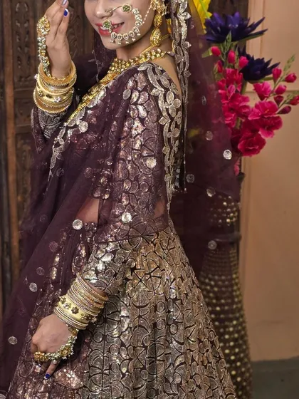 A beautiful wine-coloured lehenga with silver floral patterns. The matching jewellery set with a large nath completes this royal look.