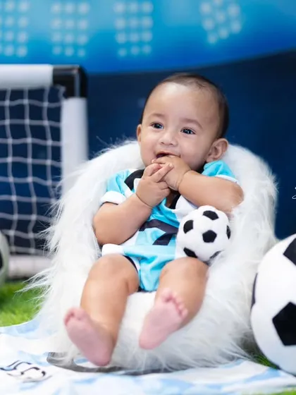 A happy future footballer surrounded by soccer balls and a goal post. These themed sitter sessions are great for capturing their growing personalities.