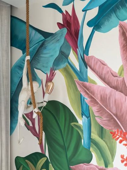 'The Whispering Palms' mural was designed to bring a playful, tropical jungle into a child's room. The hand-painted scene is filled with lush, colorful foliage and a whimsical monkey, creating a joyful and imaginative backdrop for play and dreams.