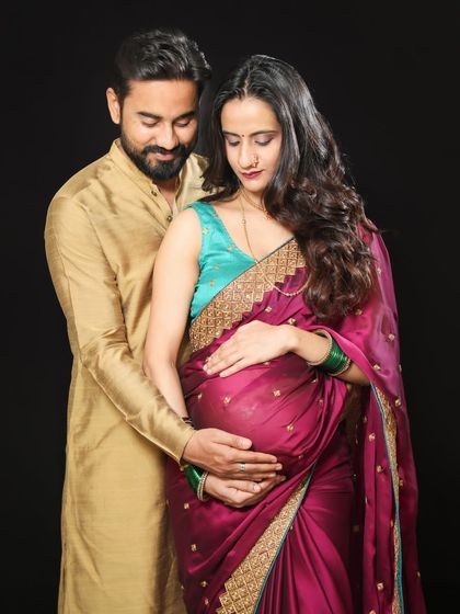 Capturing the beauty of tradition. This couple's ethnic wear, with the rich saree and kurta, makes for a stunning and meaningful maternity portrait against a classic black background.