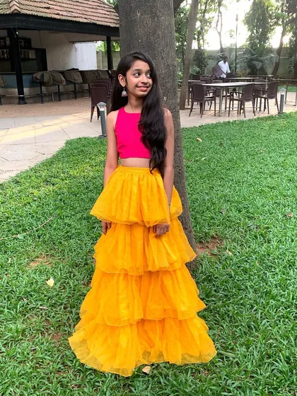 For my little clients, I design outfits that are both stylish and comfortable. This vibrant set features a simple pink crop top paired with a fun, multi-tiered yellow net skirt, perfect for any party.
