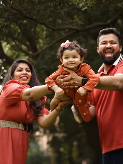 Flying high with mom and dad. This outdoor family portrait is full of energy and happiness. The natural park setting provides a beautiful backdrop for capturing candid, joyful moments like this.