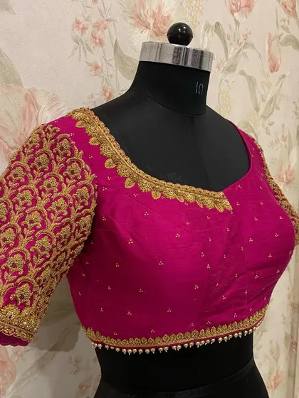 A closer look at a bridal blouse designed for wedding festivities. The sleeve is fully covered in a dense, repeating pattern of gold zardosi embroidery for a rich, textured look.