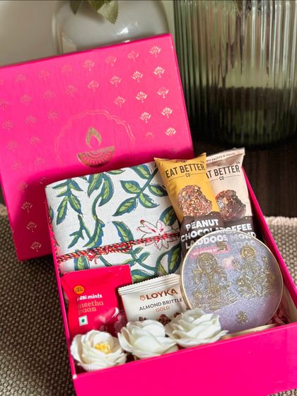 This compact and charming pink Diwali box is perfect for a thoughtful gesture. It includes a handcrafted notebook, a Ganesh and Laxmi resin stand for blessings, almond brittle, and chocolate ladoos.