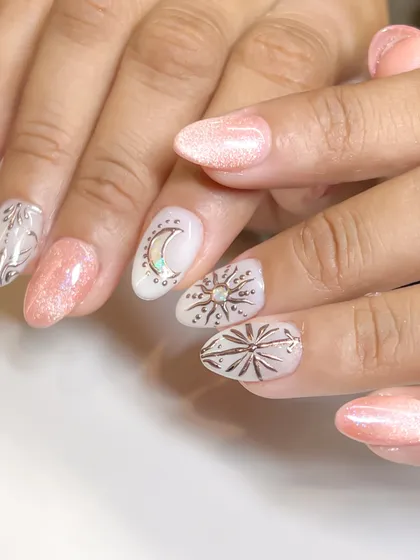 A full view of the celestial-themed nail art, with a sun, moon, and stars over a shimmery cat eye base.