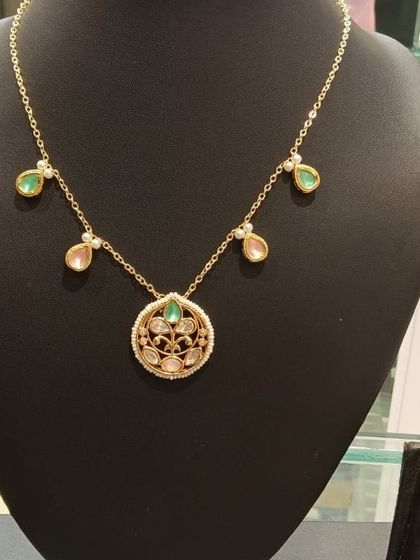 This delicate necklace features a circular filigree pendant with pastel pink and green teardrop stones. It's a beautiful, minimal piece for those who love subtle elegance.