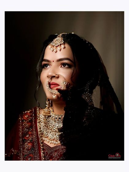 A classic, dramatic bridal portrait with the bride looking up, highlighting her features and elaborate nose ring.