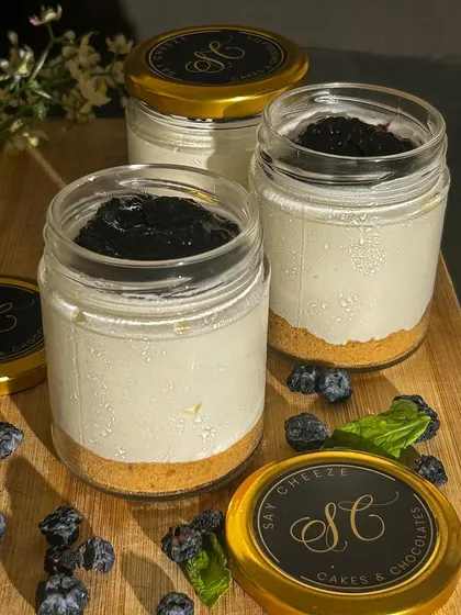 My Blueberry Cheesecake in a reusable glass jar. It features a crunchy biscuit base, a creamy cheesecake layer, and a generous topping of my homemade blueberry compote.
