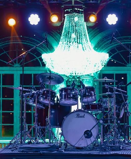 A close-up of the magnificent crystal chandelier hanging over the drum set, a perfect example of how I mix glamorous elements with the functional needs of a performance stage.
