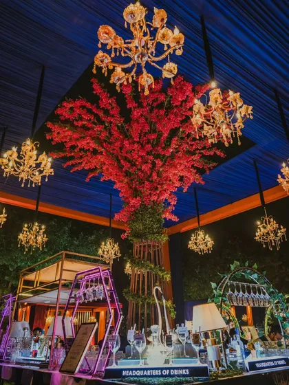 Welcome to an evening of pure opulence. ✨ I designed this magnificent bar as the heart of the celebration, featuring a striking red floral tree surrounded by a constellation of golden chandeliers. This is where I blend dramatic design with flawless function for your luxury cocktail event.