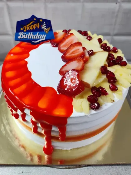 A half-and-half cake design, with one side featuring a strawberry glaze drip and the other topped with fresh fruits.