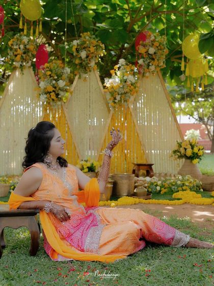 The bride relaxes against the vibrant Haldi decor. This portrait captures a moment of calm and beauty amidst the lively celebration.