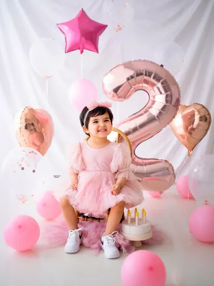Ready to celebrate! A fun shot with the birthday girl and her cake, surrounded by festive balloons.