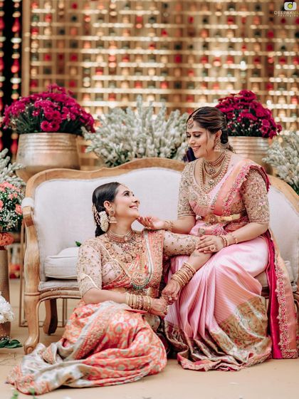 A beautiful moment between sisters. We designed these coordinating pink and peach Kanchipuram silk sarees with unique blouse designs for a family celebration.