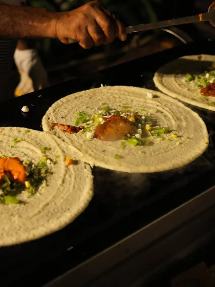 A chef at my live dosa station expertly prepares multiple dosas at once. This action shot captures the steam and sizzle, showcasing the freshness and skill involved in my South Indian catering.