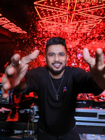 A welcoming, open-armed pose from behind the decks. This shot is all about inviting the crowd to join the party.