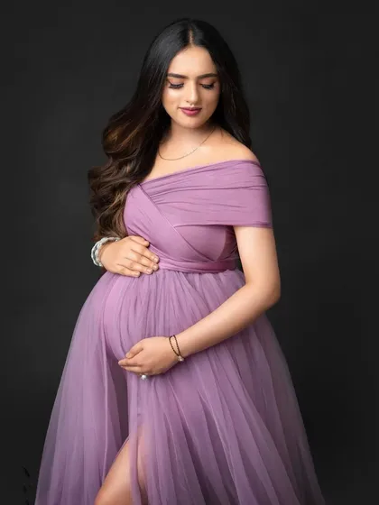 A classic and tender close-up portrait from a studio session. This shot focuses on the quiet moments and emotions of pregnancy, highlighting your glow in a beautiful lavender gown.
